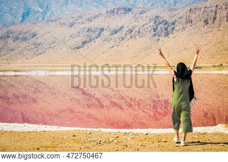 Female Traveler Tourist Stand With Hands Up Enjoy Maharlu Pink Salt Lake Shore. Travel Destination I