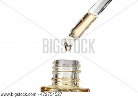 Part Of A Bottle With Yellow Cosmetic Serum. Cosmetic Glass Pipette With A Yellow Oily Drop Of Serum