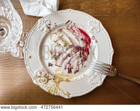 Dirty Plate After Eaten Dessert On The Wooden Table With Fork, Empty Glass And Used Napkin