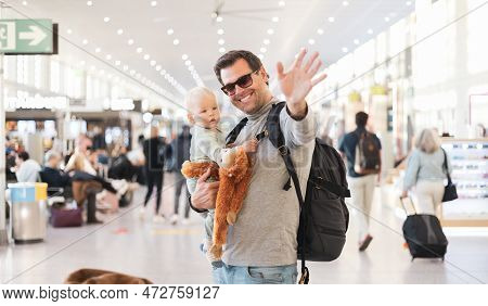 Father Traveling With Child, Holding His Infant Baby Boy At Airport Terminal Waiting To Board A Plan