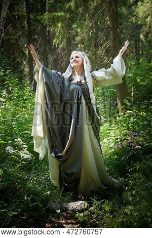 Adult Mature Woman 40-60 In A Green Long Fairy Dress In Forest. Photo Shoot In Style Of Dryad And Qu