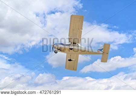 Single Engine Ultralight Plane Flying In The Blue Sky With White Clouds