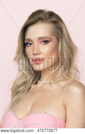 A Beautiful Attractive Woman With Blonde Hair In A Stunning Pink Dress On A Pink Background. Fashion