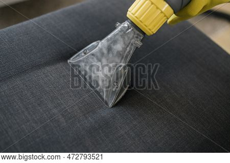 Man Holding Modern Washing Vacuum Cleaner And Cleaning Dirty Sofa With Professionally Detergent. Pro