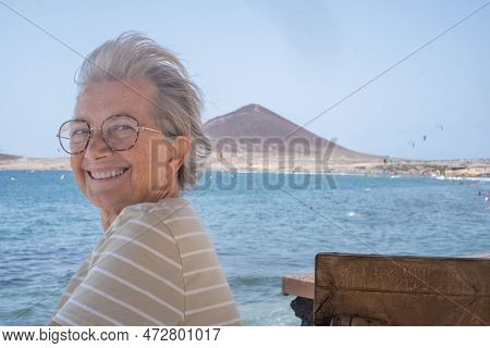 Portrait Of Happy Senior Woman Sitting Near The Beach Looking At Camera - Elderly Beautiful Lady Rel