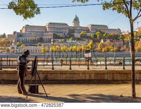 Statue Of Artist Ignac Roskovics On Danube Embankment With Royal Palace Of Buda At Background, Budap