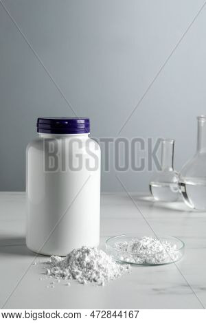 Calcium Carbonate Powder, Jar And Laboratory Glassware On White Marble Table