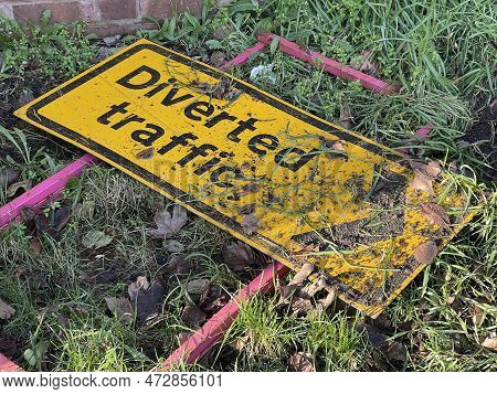Cropped Shot Of Diverted Traffic Sign Thrown Away In The Grass Covered In Mud