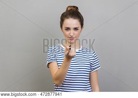 Come Here. Portrait Of Woman Wearing Striped T-shirt Calling You With Finger, Looking At Camera With