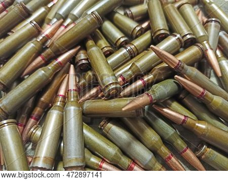 Cartridges For The Kalashnikov Assault Rifle. War Concept. Pile Of Cartridges With Bullets. Means Of