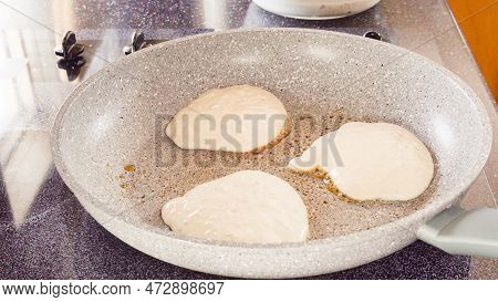 Frying Pancakes In A Frying Pan Over The Electric Stove.