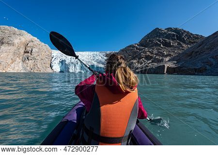 Young Woman Kayaking Mosevatnet Lake With Folgefonna Glacier In The Background, Visiting Norway
