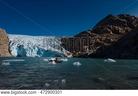Young Woman Kayaking Mosevatnet Lake With Folgefonna Glacier In The Background, Visiting Norway