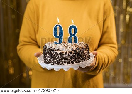 Happy Birthday. Woman Holding Fresh Delicious Birthday Cake With Burning Candle Number 98, Close Up.