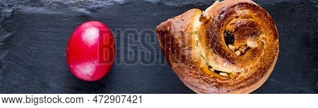 Red Easter Egg And Sweet Bun On A Black Stone Surface. Close Up Photo.