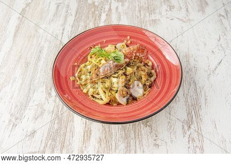 Italian Recipe For Tagliatelle Di Mare. Seafood Stew Over Fresh Pasta Presented On A Red Plate