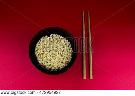 Block Of Instant Noodles In A Wooden Bowl On A Red Table Top With Chopsticks