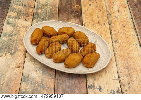 White Porcelain Tray With A Generous Portion Of Assorted Croquettes Of Serrano Ham And Cod On A Wood