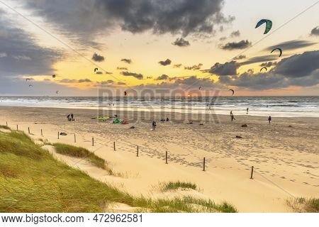 Kitesurfing Seen From The Dunes At Sunset. Kite Surf People Activity On The Beach Under Setting Su A