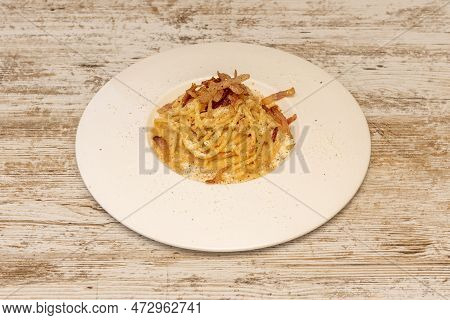 Delicious Spaghetti Dish With Carbonara Sauce And Guanciale With Grated Parmesan Cheese On White Pla