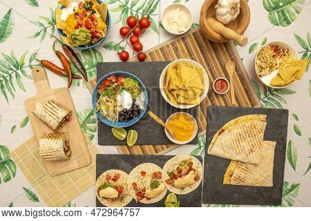 Overhead Shot Of Popular Mexican Dishes, Burritos, Nachos With Guacamole, Veal Alambre, Chicken Ting