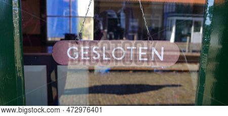 An Old Fashioned Wooden Plate Hanging On A Chainwith The Word 'gesloten' Which Means Closed.
