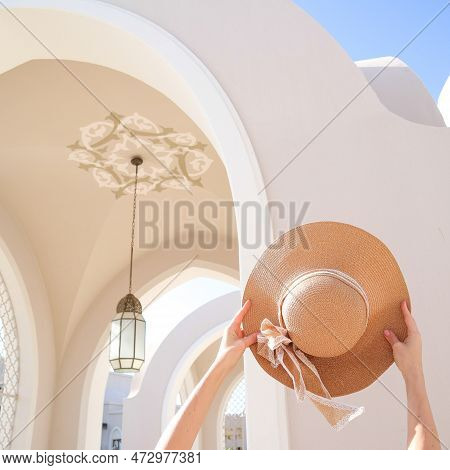The Girl Is Holding A Summer Hat On Vacation. Sunshine. Resort. High Quality Photo