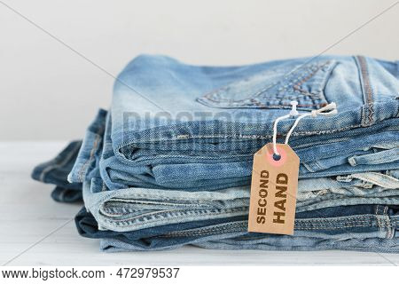 Stack Of Blue Jeans And Tag With Inscription Second Hand On White Background. Second Hand Clothing S