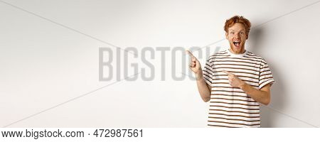Cheerful Man With Red Hair Checking Out Promo Offfer, Pointing Left At Logo And Smiling At Camera, S