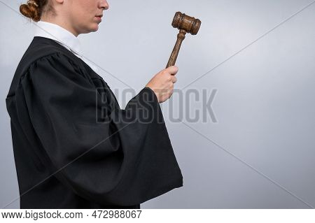 Steadfast Female Judge In A Robe Holding A Court Gavel.