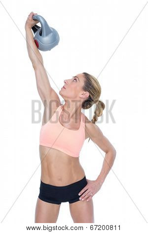 Female blonde crossfitter lifting kettlebell above head on white background