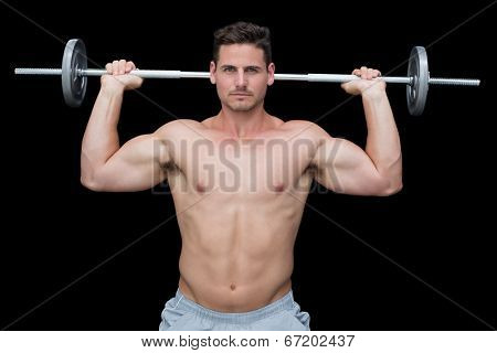 Serious handsome crossfitter lifting up barbell behind head on black background