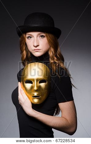 Redhead woman in hat  iwith mask in hypocrisy consept against grey background