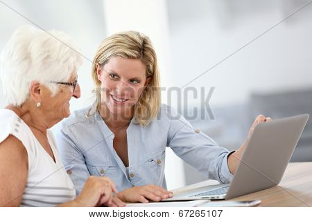 Homecarer with elderly woman using laptop computer