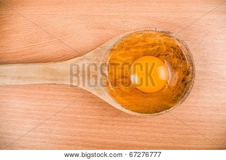 open egg on wooden spoon