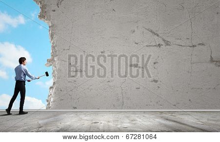 Young determined businessman with hammer in hands