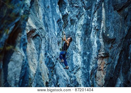 Rock climber climbing up a cliff