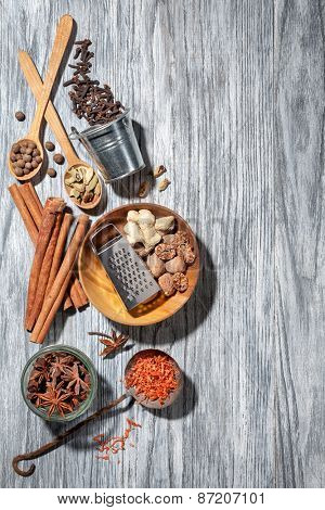 Various spices on wooden background - anise, cardamon, cinnamon, ginger, clove, nutmeg, papper and saffron