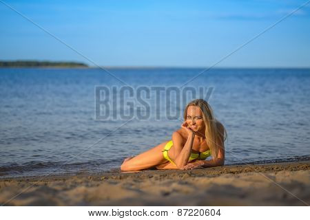 young woman in green bikini posing on a beach