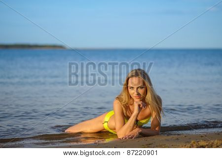 young woman in green bikini posing on a beach