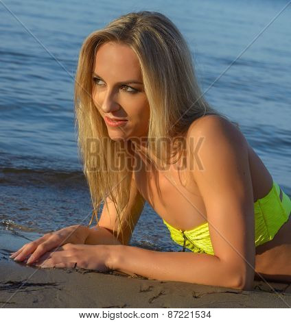 young woman in green bikini posing on a beach