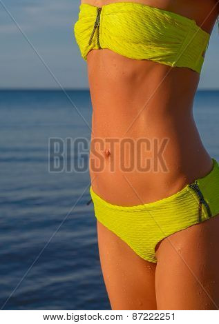 young woman in green bikini posing on a beach