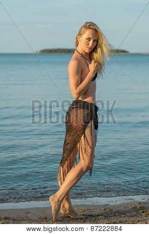 young woman in black bikini posing on a beach