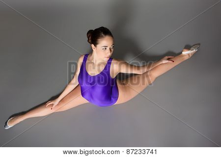 Young Female Contortionist In Purple Leotard On Dark Background