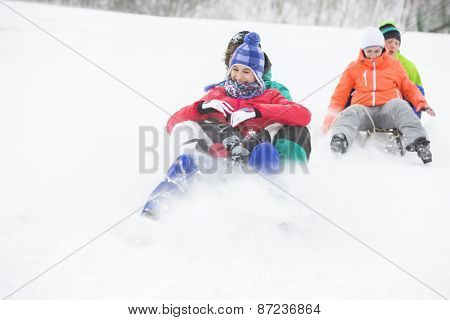 Young couples enjoying sled ride on snow covered slope