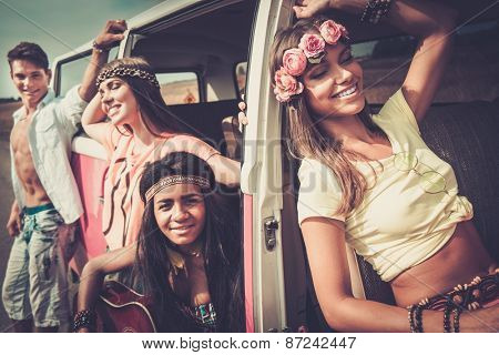 Multi-ethnic hippie friends with guitar on a road trip