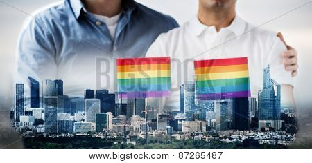 people, homosexuality, same-sex marriage, gay and love concept - close up of happy male gay couple hugging and holding rainbow flags over city background