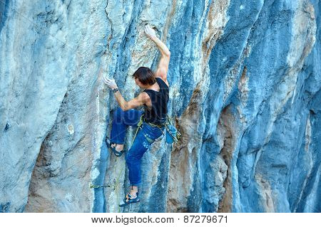 Rock climber climbing up a cliff