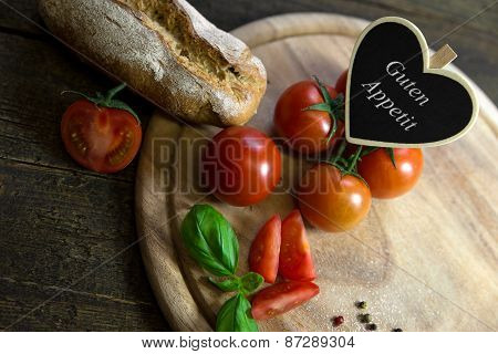 Tomatoes, Basil And Bread On A Wooden Table, Heart With Text Guten Appetit