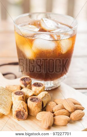Glass Of Black Iced Coffee With Some Snack
